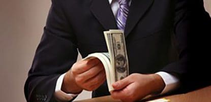 businessman flipping through hundred dollar bills