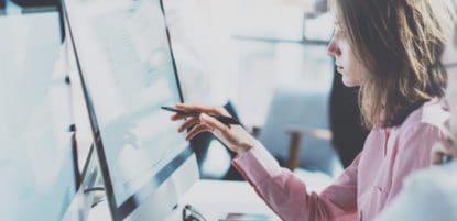 Woman pointing to computer screen with pen in hand