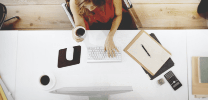 birds eye view of woman orkin on computer with coffee in hand