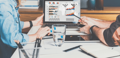 2 people analyzing data on a computer